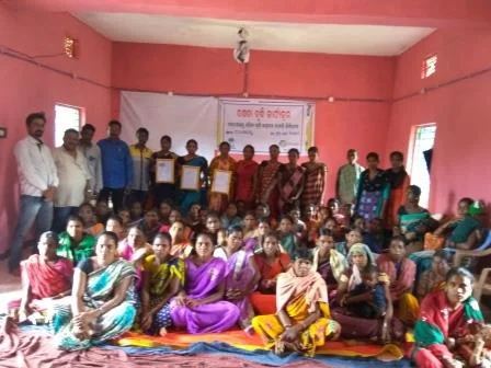 A women's group holding certificates in a village hall